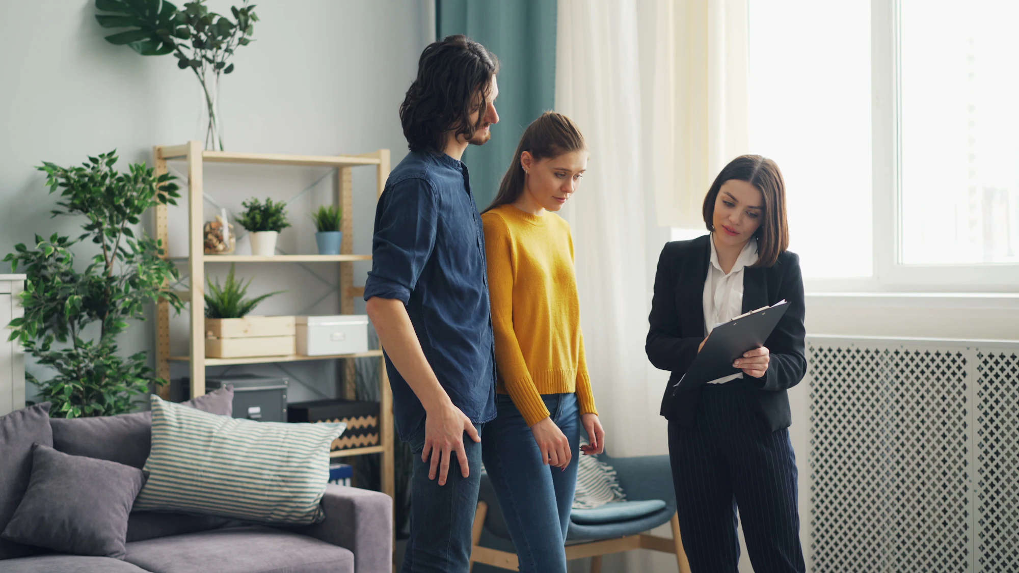 An agent walking a couple through a bright living room